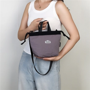 Detail of grey-purple nylon drawstring bag showing adjustable strap and brand label