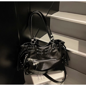 Détail d'un sac cabas en cuir brillant noir avec cordon de serrage et rivets métal