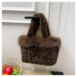 Detail of plush leopard print faux fur tote bag hanging on a black door handle