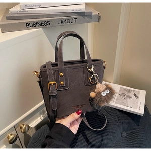 Detail of grey matte bucket bag with golden studs and cute plush monster charm