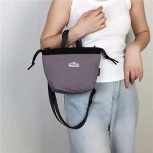 Detail of lilac nylon crossbody bag with drawstring closure and black adjustable straps