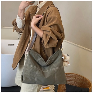 Selfie miroir montrant le sac cabas vert olive avec coutures blanches et breloque
