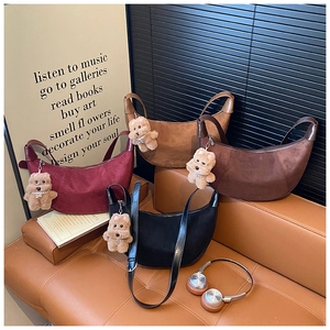 Close-up of four suede crescent bags in burgundy, khaki, brown, and black with puppy charms