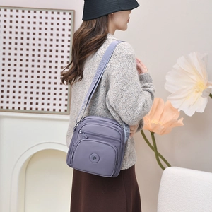 Detailansicht der lila Nylontasche mit mehreren Fächern und Logo-Jacquard-Schultergurt