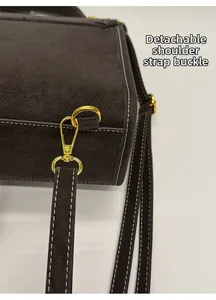 Detail des goldenen Metallhakens und abnehmbaren Riemens am braunen Lederrucksack