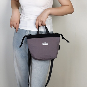 Detail of gray waterproof nylon mini bucket bag featuring drawstring closure and brand logo