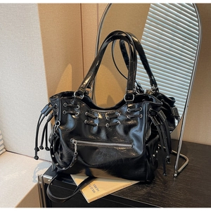 Détail d'un cabas en cuir verni noir brillant avec œillets métalliques punk et zips