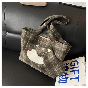 Detail der süßen Hundebestickung und des Karomusters auf der Wolltasche