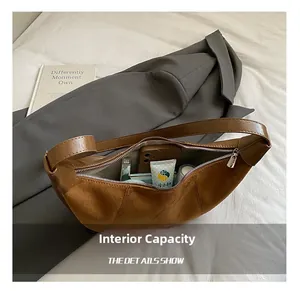 Interior view of the brown crescent bag showing storage capacity for phone and makeup