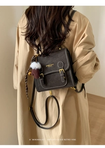 Detail eines dunkelbraunen Vintage-Lederrucksacks mit Goldschnallen und Fransenanhänger