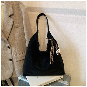 Detail of black suede hobo tote bag featuring a woven rope tassel and coffee cup charm