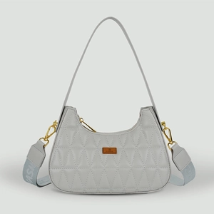 Détail du sac hobo matelassé gris clair avec large bandoulière logo et emblème métal