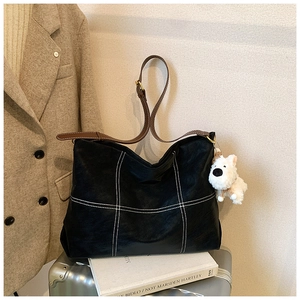 Détail du grand sac cabas noir avec coutures contrastées blanches et charm peluche
