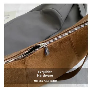 Close-up of smooth metal zipper and brown suede texture on a vintage crossbody bag