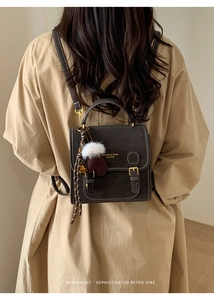 Detailansicht des braunen Lederrucksacks im Retro-Stil mit Kontrastnähten und Anhänger