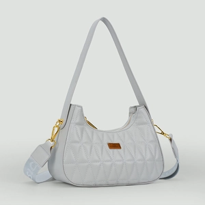 Détail d'un sac demi-lune gris matelassé avec deux bandoulières et plaque logo dorée