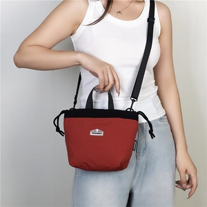 Detail view of a red and black nylon drawstring crossbody bag with an adjustable strap