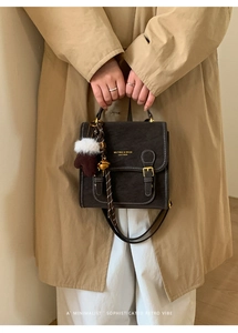 Detailaufnahme der braunen Vintage-Ledertasche mit weißen Nähten und Plüschhandschuh-Anhänger