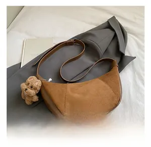 Brown suede hobo bag on grey suit jacket with plush bear charm and adjustable strap