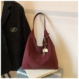Close-up of burgundy suede tote bag featuring a unique coffee cup bag charm detail