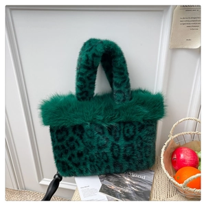 Close-up of green leopard print faux fur tote bag with fluffy trim on textured mat