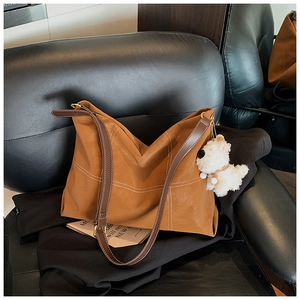 Détail du sac cabas en cuir fauve avec surpiqûres blanches et charme de chien