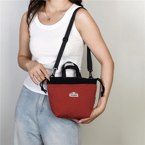 Detail view of red and black drawstring crossbody bag with adjustable shoulder strap