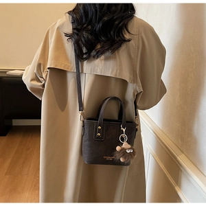 Brown matte mini tote bag with crossbody strap and cute plush monster charm detail