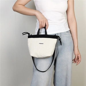 Detail of a bicolour nylon crossbody bag with crinkle texture and logo strap