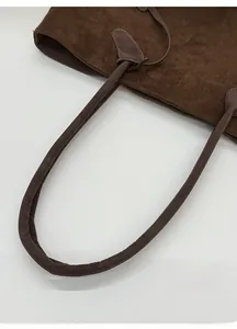 Detail of coffee brown matte suede tote showing reinforced padded round handles