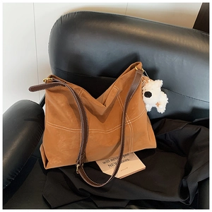 Détail du grand sac fourre-tout caramel avec coutures blanches et charme de chiot