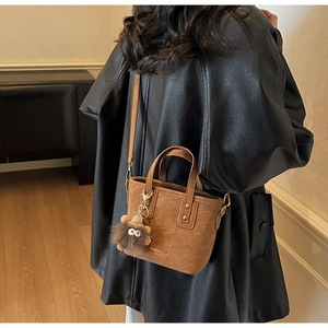 Brown frosted leather tote bag with monster charm shown in a cozy home setting