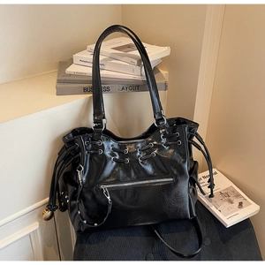 Détails du sac cabas noir brillant montrant le cuir texturé et les œillets en argent