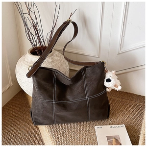 Détail d'un grand sac cabas avec coutures contrastées et pendentif chiot en peluche