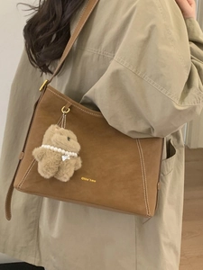Vintage brown suede hobo bag with white stitching and plush bear charm for autumn style