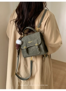 Nahaufnahme des grünen Lederrucksacks mit goldenen Metallteilen und Plüsch-Anhängern