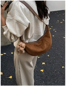 Detail of vintage brown suede hobo bag with teddy bear charm in autumn setting
