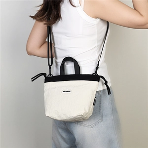 Detail of lightweight bicolor nylon crossbody bag with adjustable strap and logo label