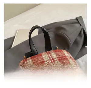 Detail of vintage plaid backpack showing faux leather handle and gold hardware zipper