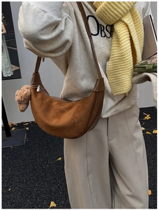 Street style view of a brown suede crescent bag with a cute bear plush keychain