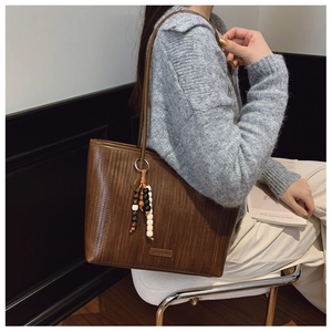 Close-up of brown woven texture tote bag with stylish wooden bead tassel charm
