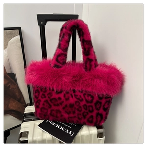 Close-up of pink leopard faux fur tote bag with plush trim on a white suitcase