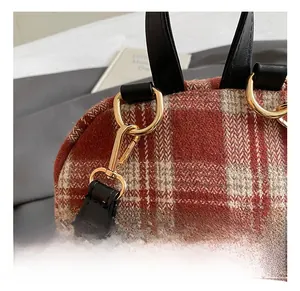 Close-up of gold metal hook hardware and red plaid woven fabric on backpack