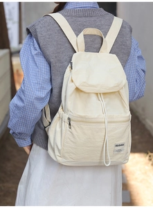 Détail sac à dos beige en nylon avec fermeture à cordon et poche zippée à l'avant