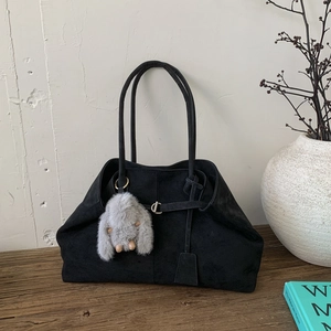 Detail of black suede tote bag with metal buckle and cute plush bunny charm