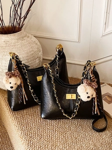 Quilted black faux leather dumpling bag with gold chain strap and teddy bear charm