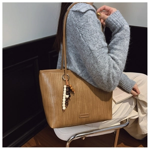 Brown woven tote bag detail showing fine texture and bohemian beaded tassel pendant