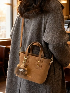 Vintage brown suede bucket bag with plush charm on a model wearing grey wool coat
