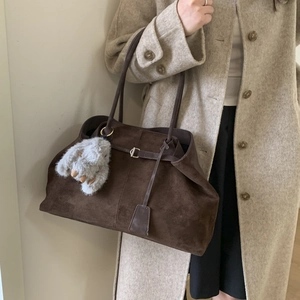 Detail of dark brown suede tote bag with decorative buckle and plush rabbit charm