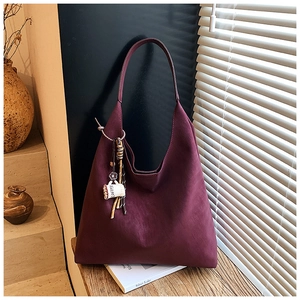 Close-up of a burgundy suede hobo bag featuring a decorative coffee cup charm on the strap